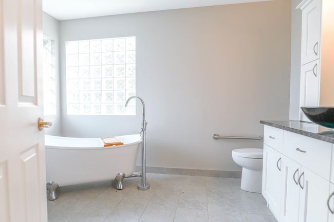 Bathroom featuring vanity, a freestanding tub, toilet, tile patterned floors, and baseboards | Image 15