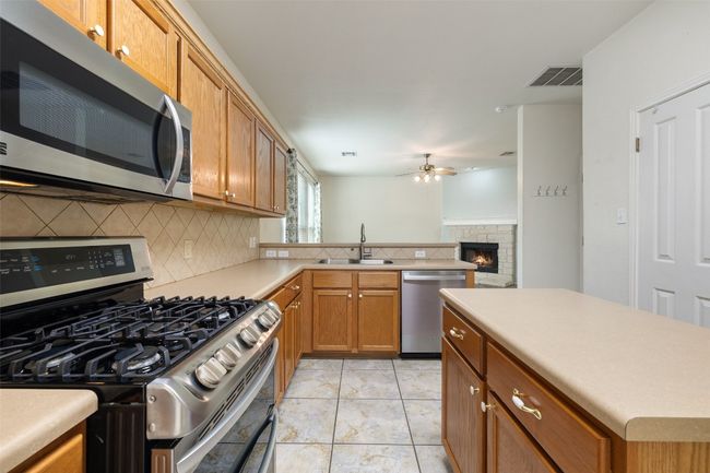 Kitchen featuring ceiling fan, a sink, stainless steel appliances, tasteful backsplash, and visible vents | Image 12