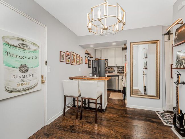Kitchen featuring appliances with stainless steel finishes, dark wood finished floors, a peninsula, a chandelier, and a kitchen bar | Image 5