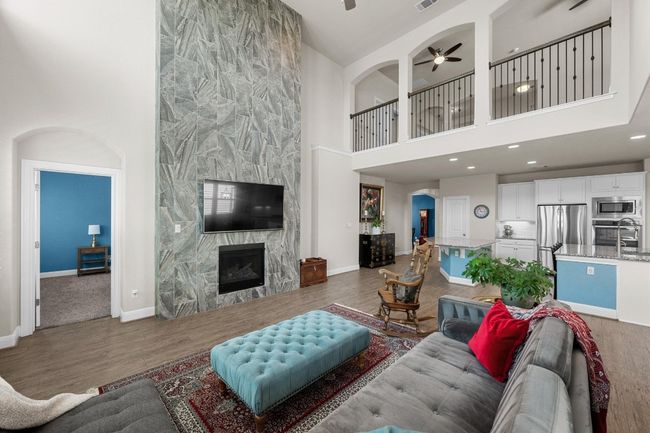 Living room featuring a towering ceiling, ceiling fan, a premium fireplace, wood finished floors, and recessed lighting | Image 7