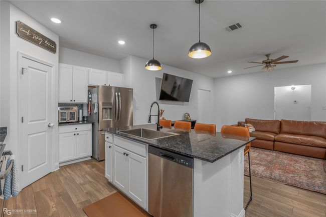 Kitchen with visible vents, a sink, an island with sink, white cabinetry, and stainless steel appliances | Image 8
