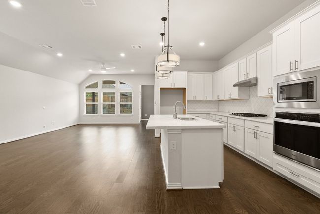 Kitchen featuring appliances with stainless steel finishes, decorative backsplash, light countertops, an island with sink, and open floor plan | Image 5
