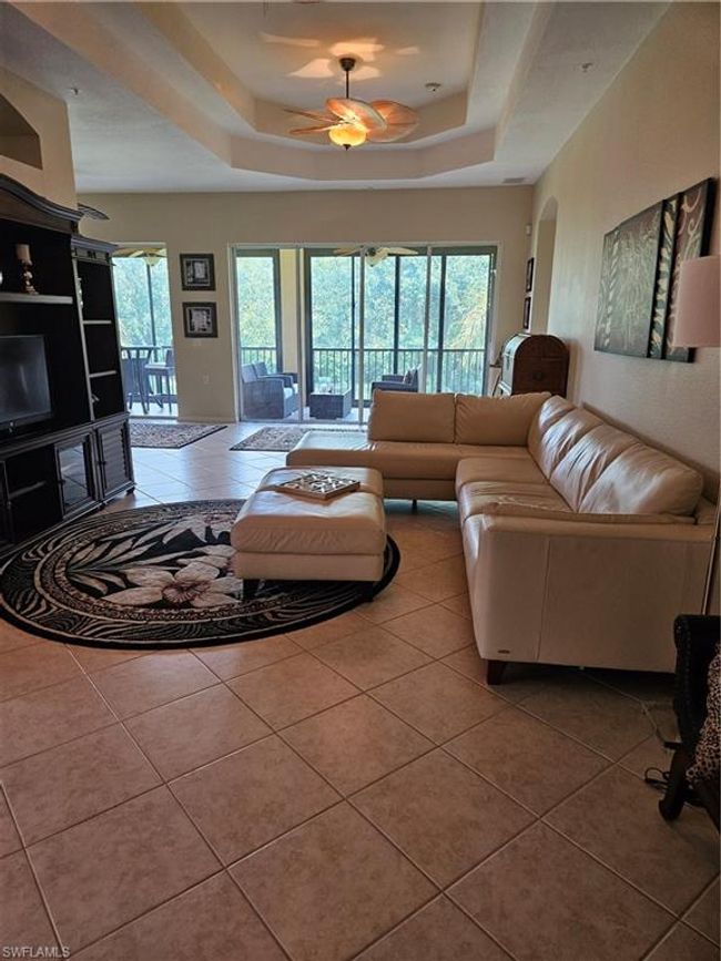 Living room with a healthy amount of sunlight, ceiling fan, a raised ceiling, and tile patterned flooring | Image 10