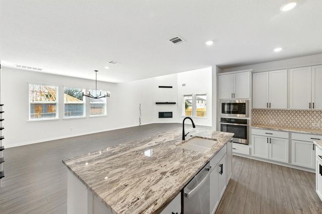 Kitchen featuring appliances with stainless steel finishes, a sink, open floor plan, light wood-type flooring, and recessed lighting | Image 14