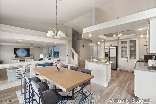 Dining space with light wood finished floors, stairway, lofted ceiling, and ceiling fan with notable chandelier | Image 12