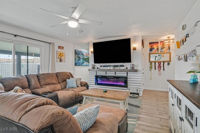 Living area with light wood finished floors, a glass covered fireplace, baseboards, and a ceiling fan | Image 11