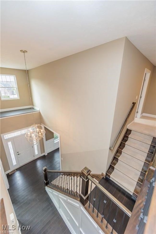 Stairs with wood finished floors and a chandelier | Image 10
