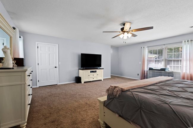 Carpeted bedroom featuring a textured ceiling, baseboards, and a ceiling fan | Image 13
