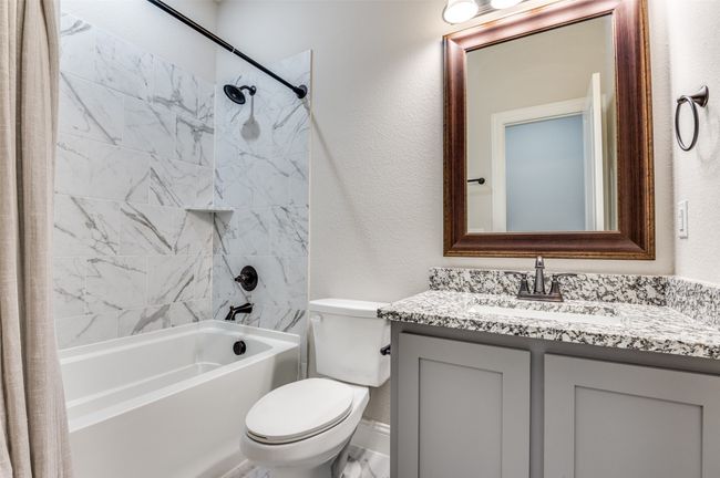 Bathroom featuring a textured wall, shower / tub combo with curtain, and vanity | Image 34