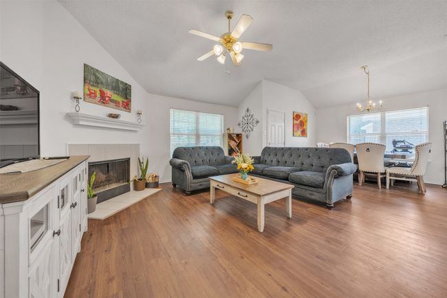 Living area featuring lofted ceiling, healthy amount of natural light, a chandelier, wood finished floors, and a fireplace | Image 4