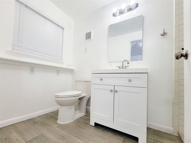 Bathroom with toilet, vanity, baseboards, and wood tiled floors | Image 8