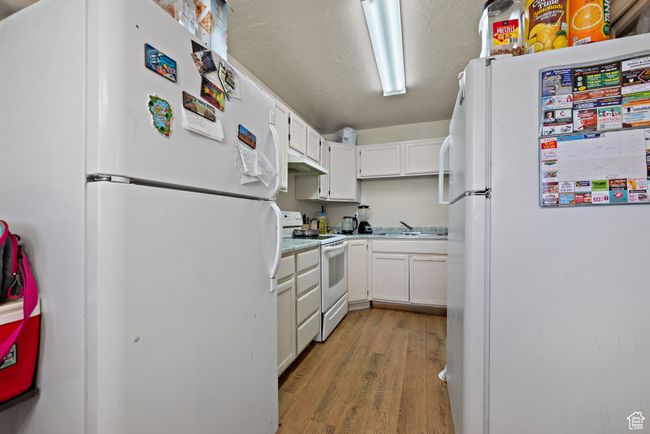 Kitchen featuring white appliances, light wood finished floors, white cabinetry, and light countertops | Image 48