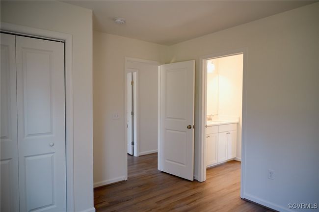 Unfurnished bedroom with connected bathroom, sink, wood-type flooring, and a closet | Image 10