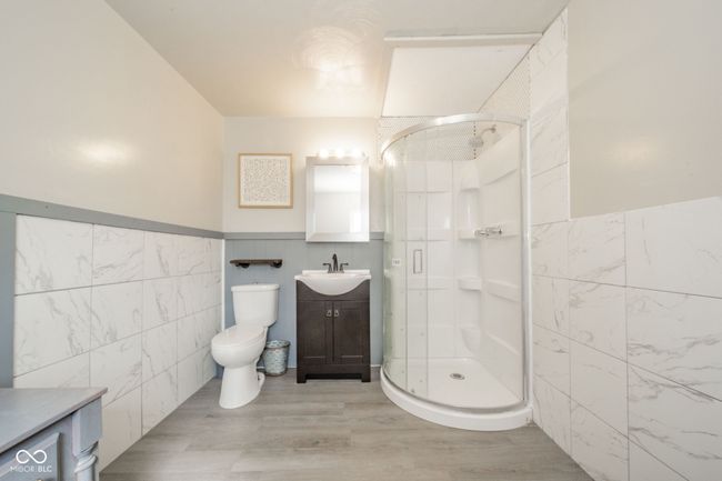 bathroom featuring toilet, vanity, tile walls, and a stall shower | Image 5