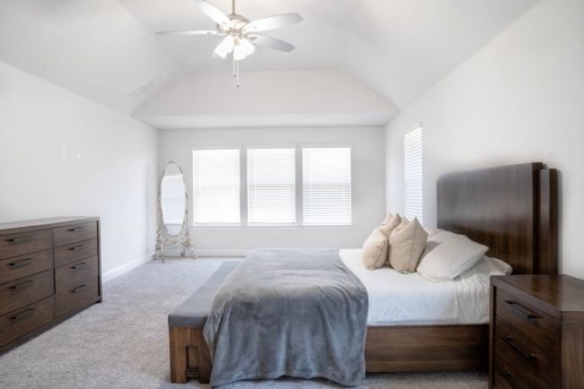 Bedroom with a ceiling fan, vaulted ceiling, carpet floors, and visible vents | Image 14