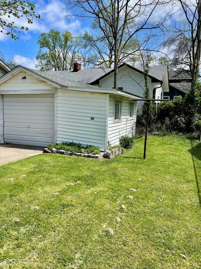 view of side of home with a shingled roof, a garage, a yard, a chimney, and concrete driveway | Image 28