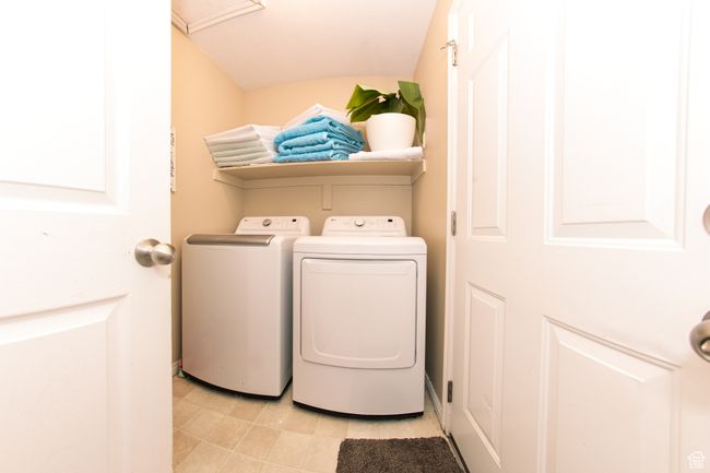 Laundry area featuring washer and dryer, laundry area, and light tile flooring. | Image 13