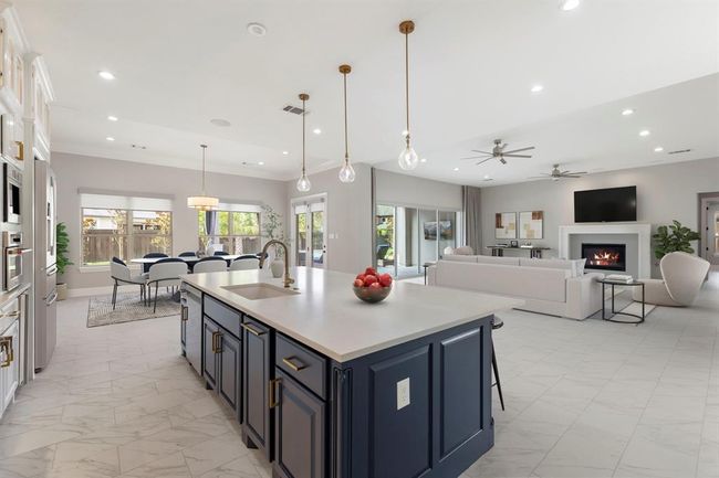 Flooded with natural light, this open-concept kitchen, dining, and living space offers effortless flow and understated luxury, where every detail—from the navy island to the cozy fireplace—invites connection and comfort. *This photo has been virtually staged.* | Image 12