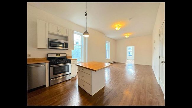 Kitchen featuring wooden counters, baseboard heating, dark wood-type flooring, white cabinetry, and stainless steel appliances | Image 15