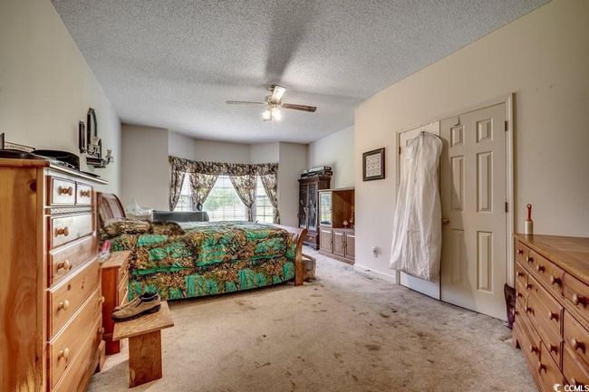 Bedroom featuring light colored carpet, a textured ceiling, and ceiling fan | Image 17