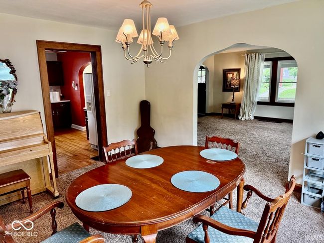 dining space featuring arched walkways, a chandelier, and carpet floors | Image 15