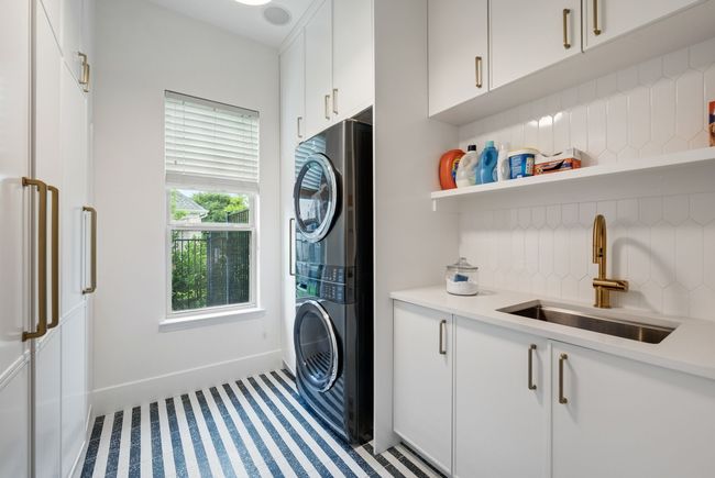 Laundry area featuring stacked washer and clothes dryer, cabinet space, and baseboards | Image 19
