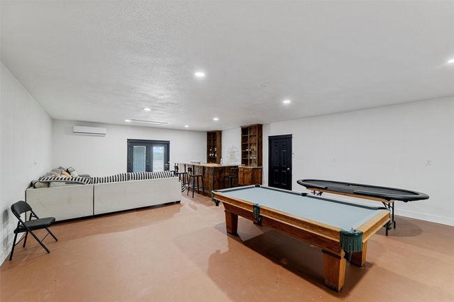 Detached man cave featuring a wall mounted AC, concrete floors, indoor wet bar, and recessed lighting | Image 39