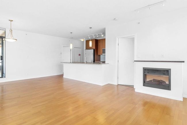 Unfurnished living room with track lighting, light wood-type flooring, and a glass covered fireplace | Image 12