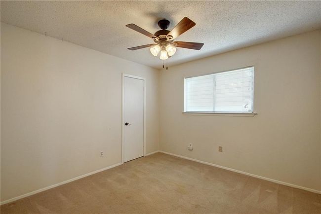 Spare room featuring a textured ceiling, light colored carpet, baseboards, and a ceiling fan | Image 21