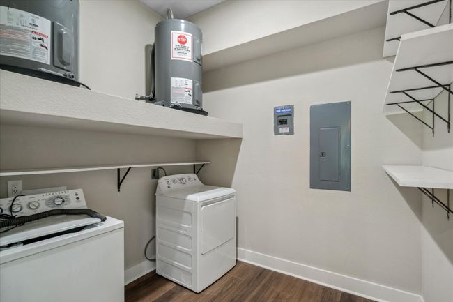 Laundry room/pantry with electric panel, washer and clothes dryer, water heater, dark wood-type flooring, and baseboards | Image 11