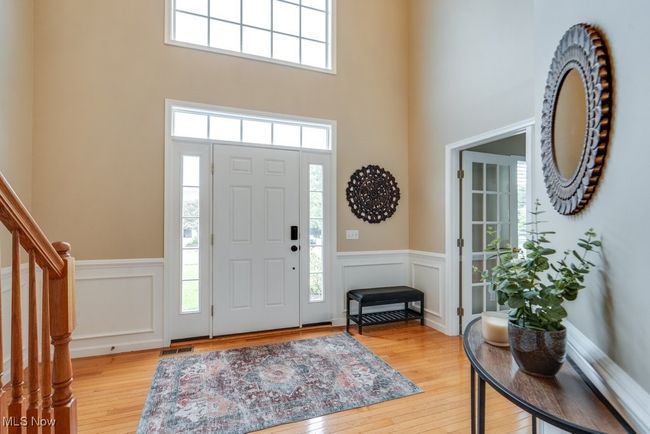Foyer entrance featuring a wainscoted wall, a high ceiling, light wood-type flooring, stairway, and a decorative wall | Image 10
