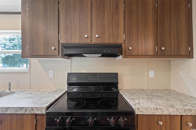 Kitchen with electric range, ventilation hood, light countertops, and backsplash | Image 12