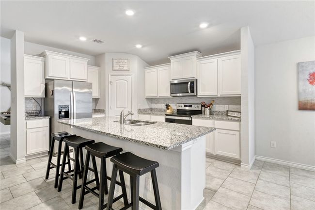 Kitchen featuring white cabinetry, appliances with stainless steel finishes, sink, and a center island with sink | Image 13