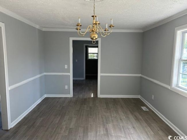 Unfurnished dining area with a chandelier, a textured ceiling, wood finished floors, healthy amount of natural light, and ornamental molding | Image 13