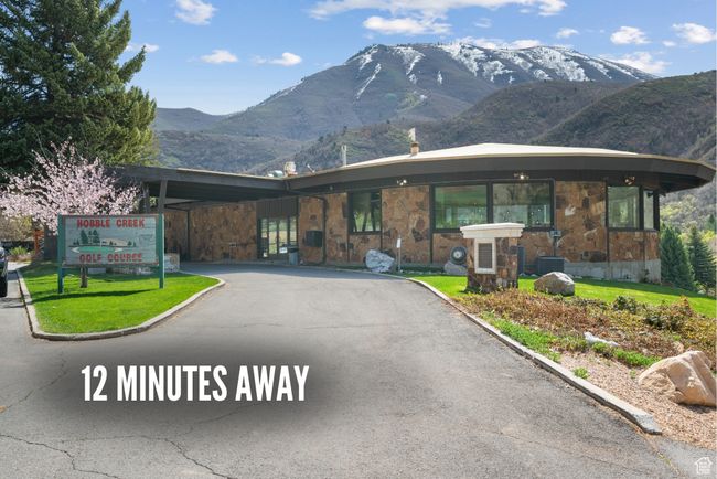 View of front of home featuring stone siding, a mountain view, and driveway | Image 6