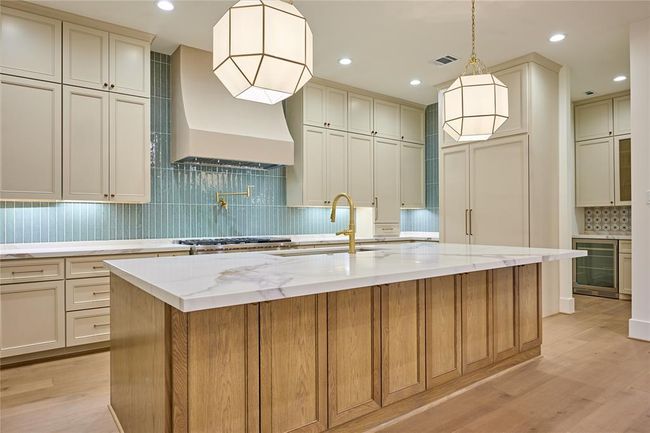 This stunning kitchen showcases a large island topped with Calacatta Macchia Vecchia quartz, offering both beauty and functionality for everyday living and entertaining. | Image 16