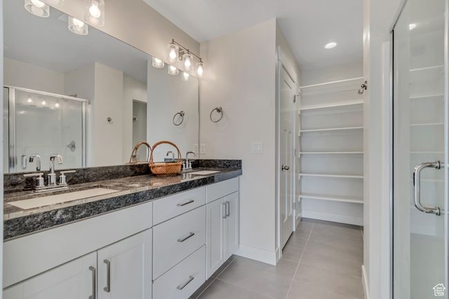 Bathroom featuring tile patterned floors, double vanity, a shower stall, and a spacious closet | Image 17