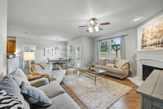 Living room with ceiling fan, a fireplace with raised hearth, and light wood finished floors | Image 16