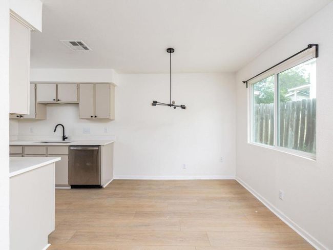 Kitchen featuring stainless steel dishwasher, a sink, light countertops, light wood-style flooring, and baseboards | Image 7