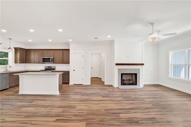 Kitchen with a kitchen island, backsplash, wood finished floors, open floor plan, and stainless steel appliances | Image 22