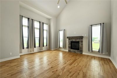 Unfurnished living room with a stone fireplace, light hardwood / wood-style flooring, and high vaulted ceiling | Image 3