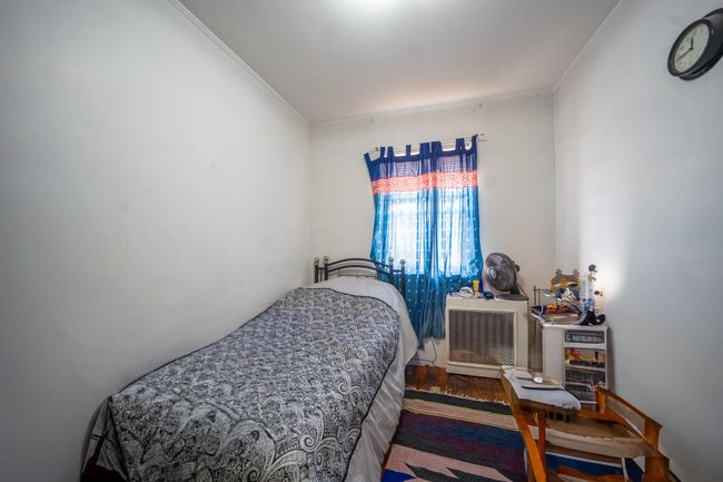 Bedroom with wood finished floors, crown molding, and radiator | Image 20