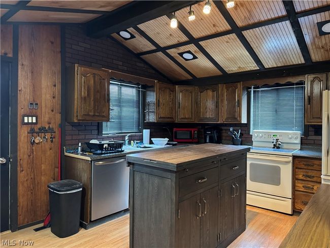 Kitchen featuring butcher block countertops, stainless steel dishwasher, light wood-type flooring, white electric range oven, and lofted ceiling with beams | Image 8