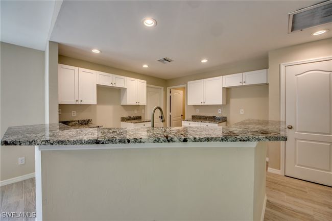 Kitchen with stone countertops, visible vents, and white cabinetry | Image 21