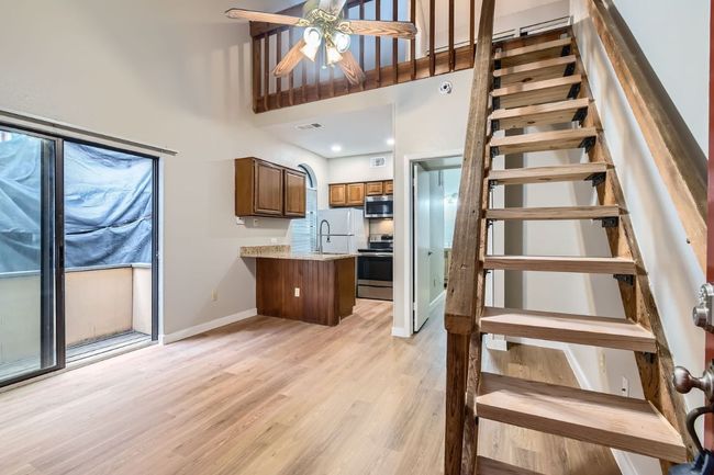 Kitchen with light wood-type flooring, brown cabinets, a peninsula, stainless steel appliances, and a ceiling fan | Image 5