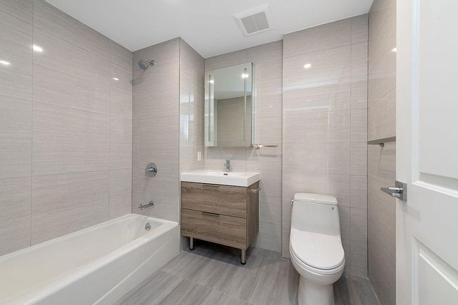 Bathroom featuring tile walls, visible vents, toilet, vanity, and shower / tub combination | Image 4