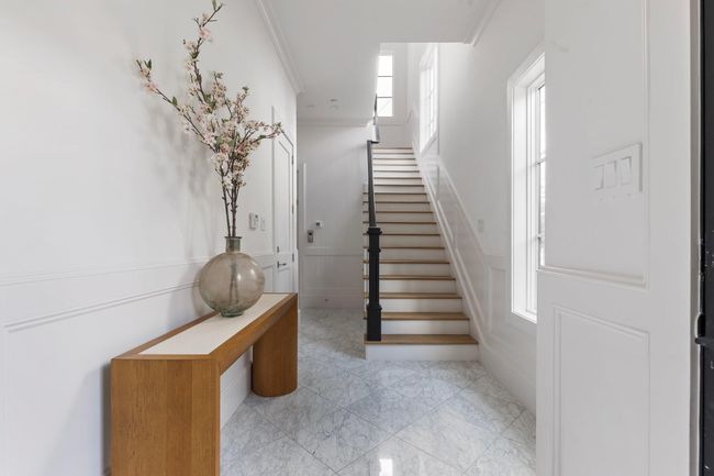 Back downstairs sits the welcoming foyer that seamlessly connects to the staircase, a private ground-floor bedroom, and convenient garage access. This thoughtfully designed space is perfect for greeting guests with its inviting layout and easy flow throughout the home. | Image 39