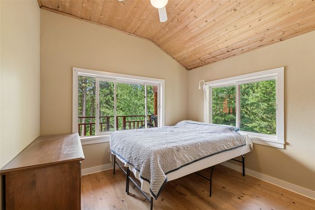 Apartment bedroom with lofted ceiling, wooden ceiling, light wood finished floors, and ceiling fan | Image 47