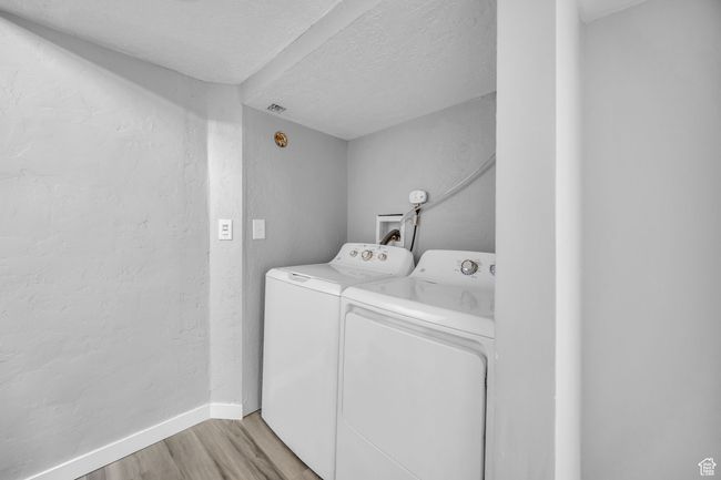 Washroom featuring independent washer and dryer, light wood-style floors, a textured ceiling, and baseboards | Image 27