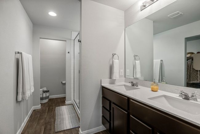 Bathroom featuring double vanity, wood finished floors, and a shower stall | Image 15